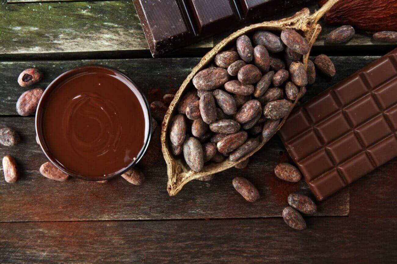 Cocoa beans and dark chocolate on wooden table